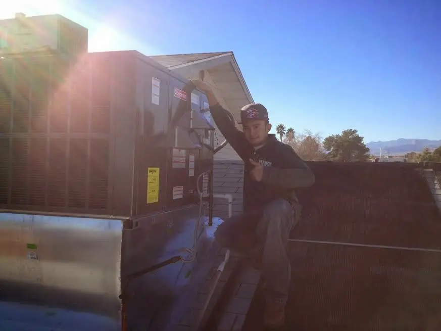 HVAC technician performing AC Tune-Up on a rooftop unit in Stanford